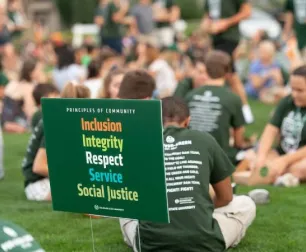 Groups of students sitting outside with a Principles of Community sign in the ground